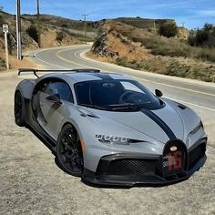 the bugatti is parked on the side of the road in front of a hill