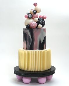 a three tiered cake with black, white and pink decorations on it's top