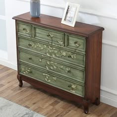 a green painted dresser sitting on top of a hard wood floor next to a white wall