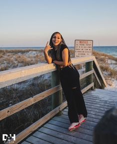 a woman standing on a boardwalk next to the ocean with her arms crossed and smiling