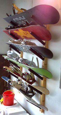 there are many snowboards on the rack in this room and one is holding a cup