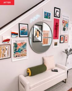 a white bench sitting under a round mirror next to a wall with pictures on it