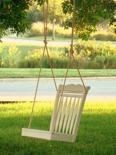 a white wooden swing hanging from a tree