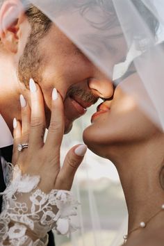 a man and woman kissing under a veil with their hands on each other's cheek