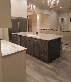 an empty kitchen with marble counter tops and stainless steel appliances in the center, surrounded by wood flooring