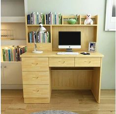 a wooden desk with a computer monitor and bookshelf in the corner, on top of a hard wood floor