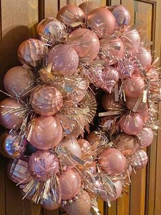 a wreath with pink and silver ornaments hanging from it's side on a door