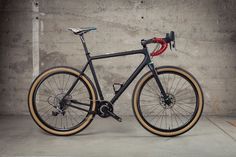 a black bike parked in front of a concrete wall with a red handlebar on it