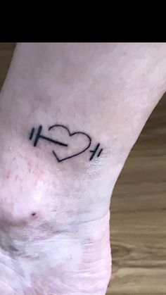 a small tattoo on the foot of a person with a heart and arrow in it