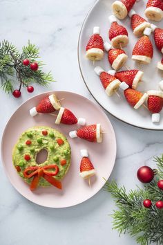 two plates with fruit and marshmallows on them, one has a pretzel in the shape of santa's hat