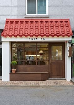 a store front with a red roof and white walls