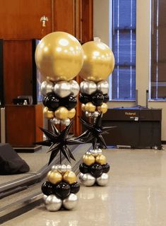 some black and gold balloons are in the middle of an office lobby with other decorations