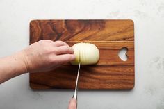 someone is cutting an onion on a wooden board