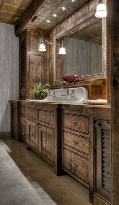 a bathroom with wooden cabinets and a large mirror on the wall over the sink is lit by two lights