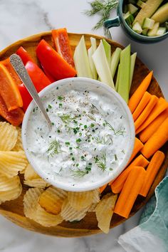 a plate with chips, carrots, celery, and dip on it