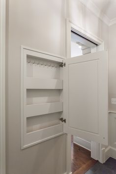 an open door in a white room with wood floors