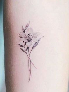 a small flower tattoo on the right side of the leg, it is white and has green leaves