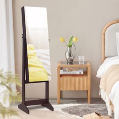 a bedroom with a bed, mirror and nightstand on the floor in front of it