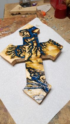 a wooden cross sitting on top of a piece of paper next to a paintbrush