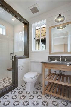 a bathroom with a sink, toilet and shower stall in the middle of it's tiled floor