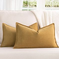 two pillows sitting on top of a white couch