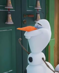 a snowman with an orange carrot sticking out of it's nose in front of a green door