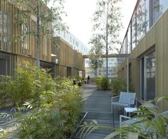 an outdoor courtyard with chairs and plants on the side walk, surrounded by tall buildings