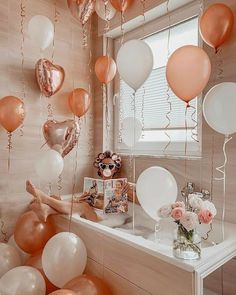 a room filled with balloons and pictures on the wall next to a table full of flowers