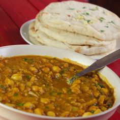 there is a bowl of soup and some pita bread on the table