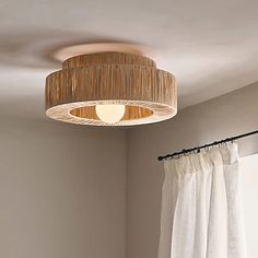 a lamp hanging from the ceiling above a bed in a room with white walls and curtains