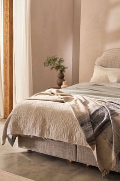 a bed sitting in a bedroom next to a window with curtains on the windowsill