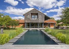 a house with a pool in front of it on the grass and trees around it