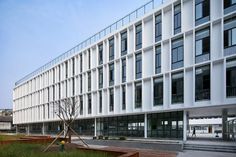 the building is white and has many windows on each side, along with wooden benches in front of it