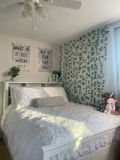 a white bed sitting in a bedroom next to a window with curtains on the windowsill