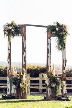 two wooden mirrors with flowers and greenery on them in the middle of a field