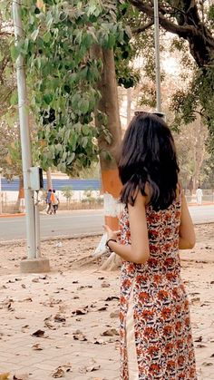 a woman in a floral dress standing under a tree