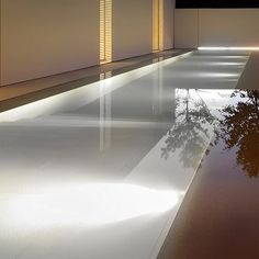 an empty swimming pool with lights shining on it's sides and trees in the water