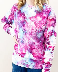 a woman standing in front of a white wall wearing a pink and blue tie dye sweatshirt