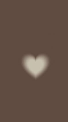 a blurry image of a white heart in the middle of a dark brown background