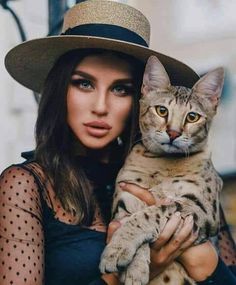 a woman wearing a hat holding a cat