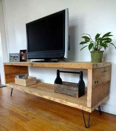 a flat screen tv sitting on top of a wooden shelf next to a potted plant