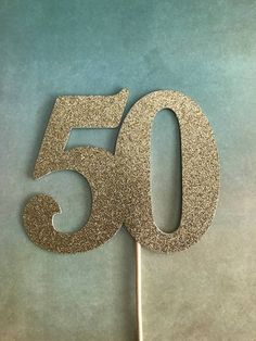 a cake topper with the number fifty five on it's stick in gold glitter