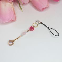 a pink flower and some beads on a black cord with a gold charm attached to it