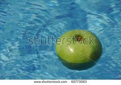 an apple floating in the water on top of a blue swimming pool with ripples