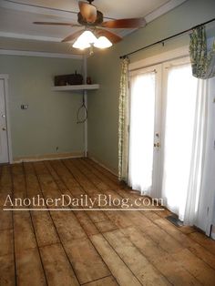 an empty living room with hard wood flooring and ceiling fan in the middle of the room