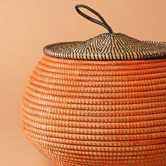 an orange and black basket with a handle on the top that is made out of wicker