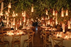 the tables are set with candles and place settings for an elegant dinner or reception in front of hanging lanterns