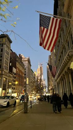 an american flag hanging from the side of a building on a city street at night