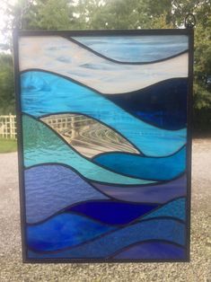 a stained glass window sitting on the side of a road with trees in the background