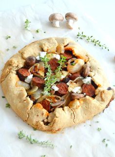 a pizza sitting on top of a white paper covered in cheese and toppings next to mushrooms